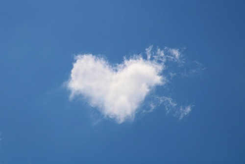 Herzförmige weiße Wolke vor blauem Himmel